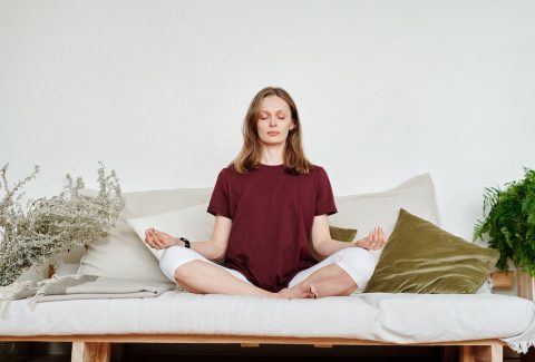 woman in red shirt sitting on couch meditating